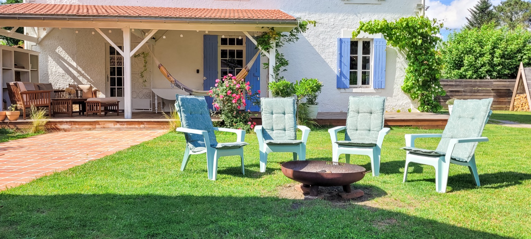 Jardin brasero chaises hamac volets bleus